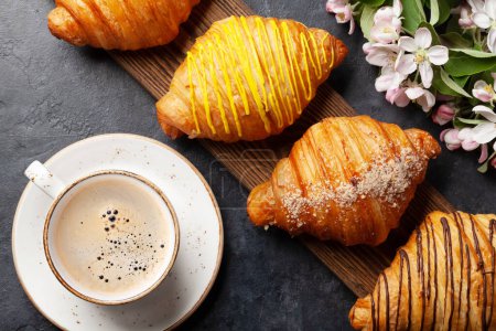 Foto de Varios croissants sobre tabla de madera y café. Desayuno francés. Vista superior plano laico - Imagen libre de derechos