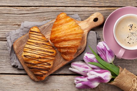 Foto de Varios croissants, taza de café y ramo de tulipanes. Desayuno francés. Vista superior plano laico - Imagen libre de derechos