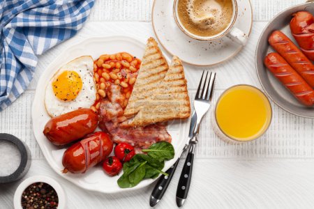 Foto de Desayuno inglés con huevos fritos, frijoles, tocino y salchichas. Café y jugo de naranja. Vista superior plano laico - Imagen libre de derechos