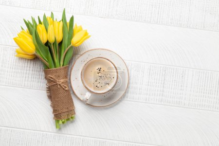 Téléchargez les photos : Bouquet de fleurs de tulipe jaune et tasse à café sur table en bois. Vue du dessus plat avec espace de copie - en image libre de droit