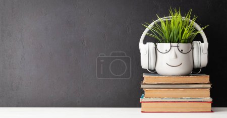 Téléchargez les photos : Table avec livres et plantes avec lunettes et écouteurs. Concept de travail et d'éducation. Avec espace de copie - en image libre de droit