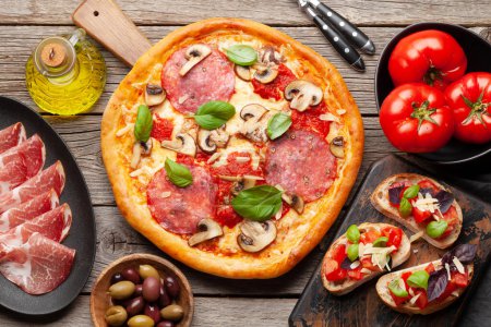 Photo for Italian cuisine. Pepperoni pizza and toasts. Flat lay on wooden table - Royalty Free Image