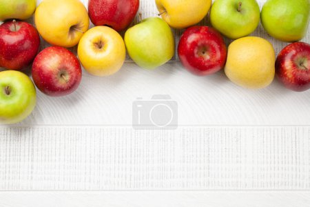 Foto de Coloridos frutos maduros de manzana sobre una mesa de madera. Vista superior plano con espacio de copia - Imagen libre de derechos