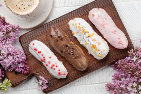 Téléchargez les photos : Dessert et café Eclair. Sur table en bois avec fleurs lilas. Vue du dessus plat lay - en image libre de droit