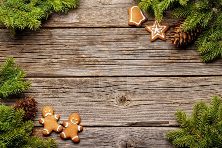 Téléchargez les photos : Sapin de Noël branches, biscuits au pain d'épice et cônes de pin sur fond de bois. Pose plate avec espace pour les salutations - en image libre de droit