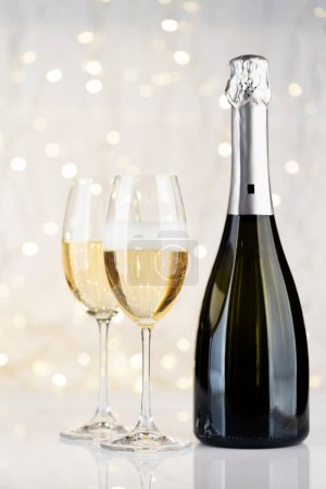 Téléchargez les photos : Bouteille de champagne et verres devant les lumières de Noël bokeh - en image libre de droit