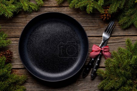 Photo for Table setting from above with empty plate, Christmas Fir tree branches and pine cones on wooden background. Flat lay - Royalty Free Image