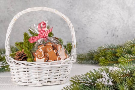 Foto de Cesta con galletas de jengibre navideño ramas de abeto. Con espacio para tus saludos de Navidad - Imagen libre de derechos