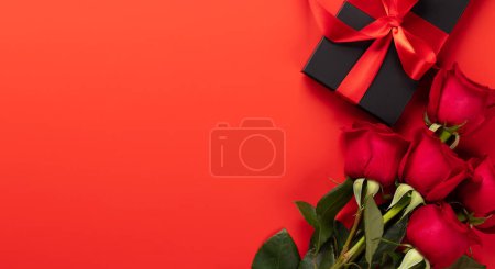 Téléchargez les photos : Carte Saint Valentin avec coffret cadeau et fleurs roses. Sur fond rouge avec espace pour vos salutations - en image libre de droit