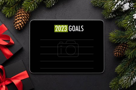 Téléchargez les photos : Tablette avec le modèle d'objectifs de l'année prochaine, boîtes-cadeaux et décor de Noël. Modèle d'écran de l'appareil de Noël - en image libre de droit