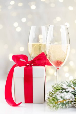 Foto de Copas de champán y caja de regalo frente a las luces de Navidad bokeh - Imagen libre de derechos