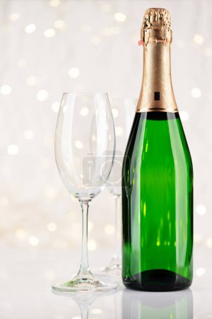 Foto de Botella de champán y copas frente a las luces de Navidad bokeh - Imagen libre de derechos