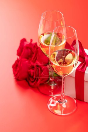 Téléchargez les photos : Carte Saint Valentin avec champagne, fleurs roses et coffret cadeau. Sur fond rouge avec espace pour vos salutations - en image libre de droit