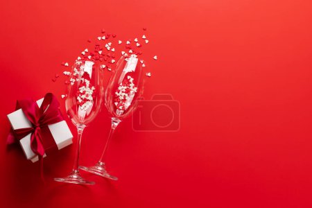 Photo for Valentines day card with champagne glasses and heart shaped sweets. On red background with space for your greetings - Royalty Free Image