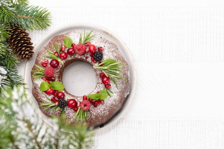 Téléchargez les photos : Gâteau de Noël décoré de graines de grenade, de canneberges et de romarin. Pose plate avec espace de copie - en image libre de droit