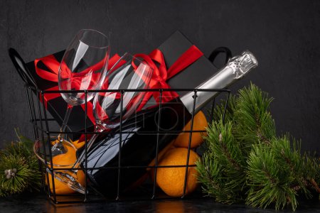 Téléchargez les photos : Panier avec coffrets cadeaux de Noël, champagne, oranges et décor - en image libre de droit