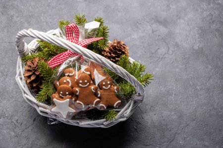 Foto de Cesta con galletas de jengibre navideño ramas de abeto. Piso con espacio para tus saludos de Navidad - Imagen libre de derechos