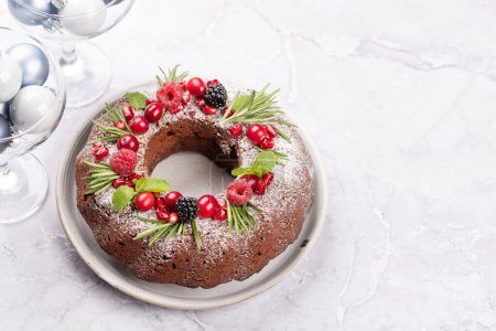 Photo for Christmas cake decorated with pomegranate seeds, cranberries and rosemary. With copy space - Royalty Free Image