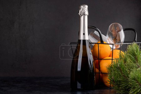 Foto de Cesta con naranjas, champán y rama de abeto. Regalo de Navidad con espacio de copia para sus saludos - Imagen libre de derechos