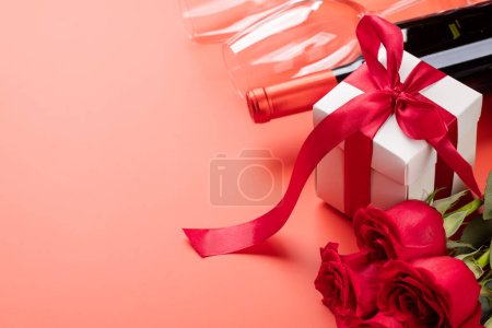 Photo for Valentines day card with wine, rose flowers and gift box. On red background with space for your greetings - Royalty Free Image