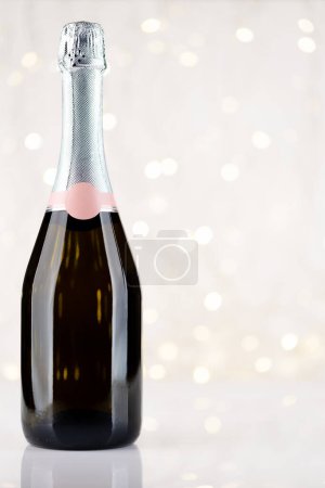 Foto de Botella de champán frente a las luces de Navidad bokeh con espacio para sus saludos - Imagen libre de derechos