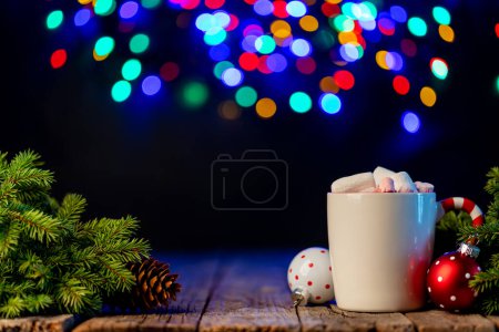 Photo for Hot chocolate with marshmallow, Christmas tree branch with decor and garland bokeh - Royalty Free Image