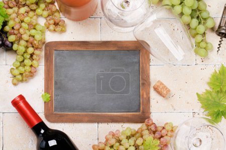 Photo for Wine glasses, bottles and grapes. Flat lay with chalkboard copy space - Royalty Free Image