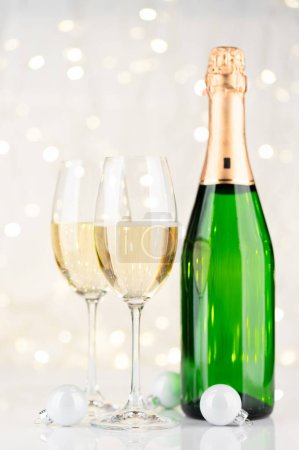 Foto de Botella de champán y copas frente a las luces de Navidad bokeh - Imagen libre de derechos
