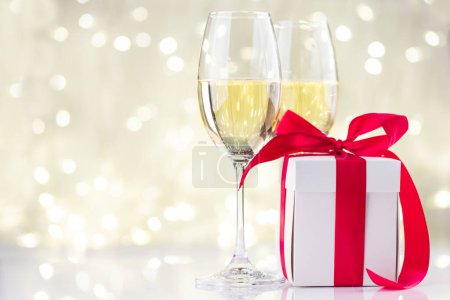 Foto de Copas de champán y caja de regalo frente a las luces de Navidad bokeh - Imagen libre de derechos