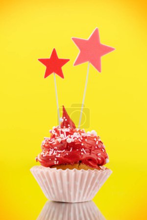 Photo for Red cream cupcake with decor on yellow background with copy space - Royalty Free Image