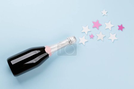Foto de Botella de champán y decoración de estrellas sobre fondo azul. Piso con espacio de copia - Imagen libre de derechos