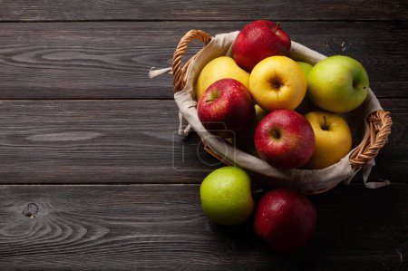 Photo for Colorful ripe apple fruits in basket on wooden table. With copy space - Royalty Free Image