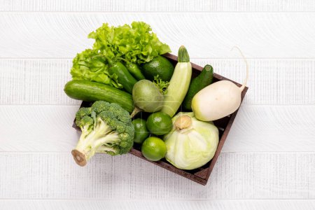 Photo for Wooden box full of healthy green vegetables and fruits. Flat lay - Royalty Free Image
