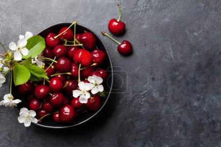 Photo for Ripe cherry in bowl with cherry blossom flowers. Top view flat lay with copy space - Royalty Free Image