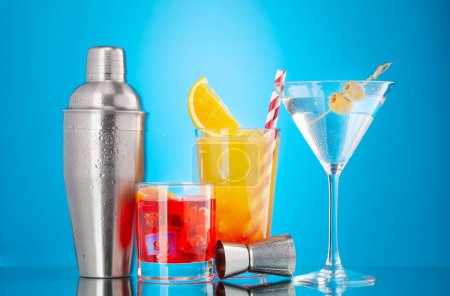 Photo for Cocktail shaker and negroni, tequila sunrise and martini cocktails on blue background - Royalty Free Image