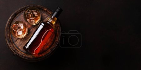 Téléchargez les photos : Bouteille de whisky écossais, verre et vieux tonneau en bois. Avec espace de copie. Vue du dessus plat lay - en image libre de droit