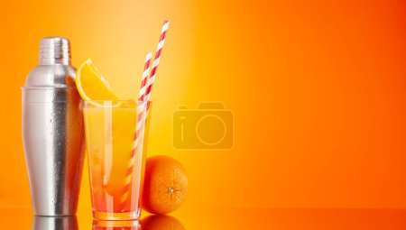 Photo for Cocktail shaker and tequila sunrise cocktail on orange background with copy space - Royalty Free Image