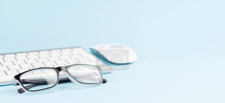 Foto de Teclado PC y gafas sobre fondo azul con espacio para copiar - Imagen libre de derechos