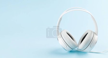 Photo for White headphones over blue background with copy space. Podcast, audiobook or music template - Royalty Free Image