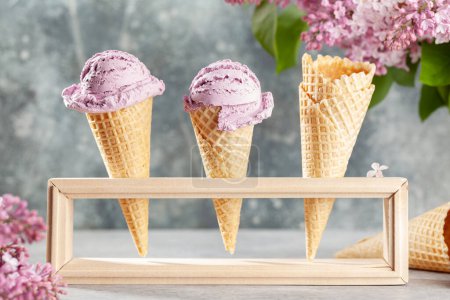 Téléchargez les photos : Divers sundae à la crème glacée dans des cônes de gaufres et des fleurs lilas - en image libre de droit