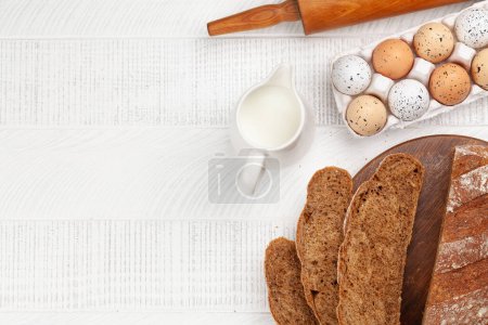 Téléchargez les photos : Trancher le pain fait maison et les ingrédients sur une table en bois. Pose plate avec espace de copie - en image libre de droit