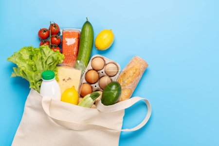 Téléchargez les photos : Sac plein d'aliments sains sur fond bleu. Pose plate avec espace de copie - en image libre de droit
