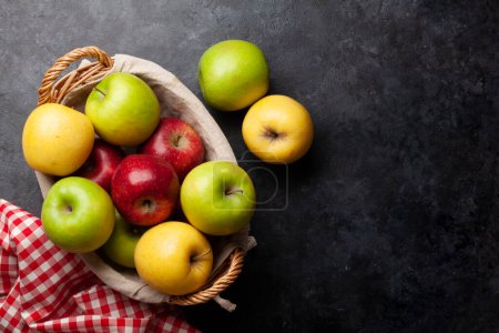 Téléchargez les photos : Fruits de pomme mûrs colorés dans le panier sur la table en pierre. Vue du dessus plat avec espace de copie - en image libre de droit