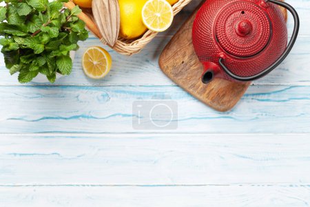 Photo for Tea with lemon and mint and teapot on wooden table. Top view flat lay with copy space - Royalty Free Image