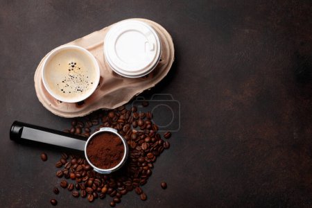 Téléchargez les photos : Café frais dans des tasses à emporter, grains de café torréfiés et café moulu dans le porte-filtre. Vue du dessus plat avec espace de copie - en image libre de droit