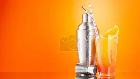 Photo for Cocktail shaker and tequila sunrise cocktail on orange background with copy space - Royalty Free Image