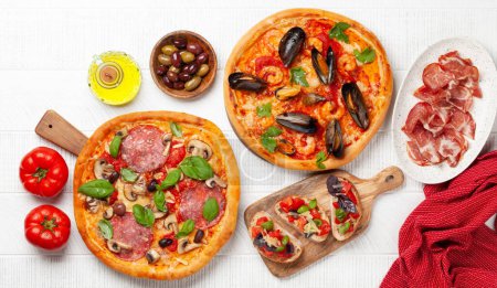 Téléchargez les photos : Cuisine italienne. Pizza aux poivrons et fruits de mer, olives et toasts antipasto. Poser à plat sur une table en bois - en image libre de droit
