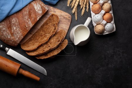 Téléchargez les photos : Trancher le pain fait maison et les ingrédients sur une table en pierre. Pose plate avec espace de copie - en image libre de droit