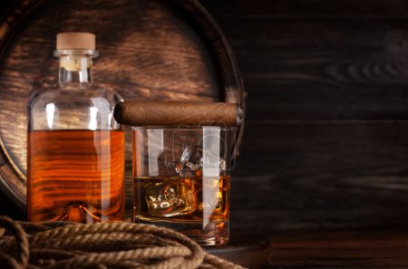 Foto de Copa y botella con coñac, whisky o ron dorado. Delante del viejo barril de madera con espacio para copias - Imagen libre de derechos