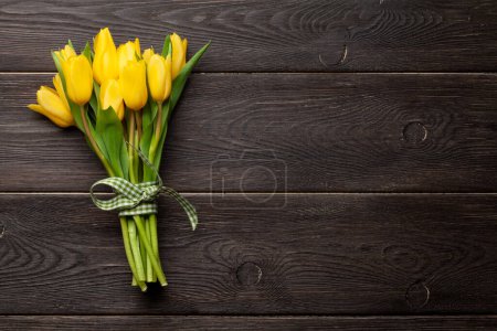 Téléchargez les photos : Bouquet de fleurs de tulipe jaune sur table en bois. Vue du dessus plat avec espace de copie - en image libre de droit